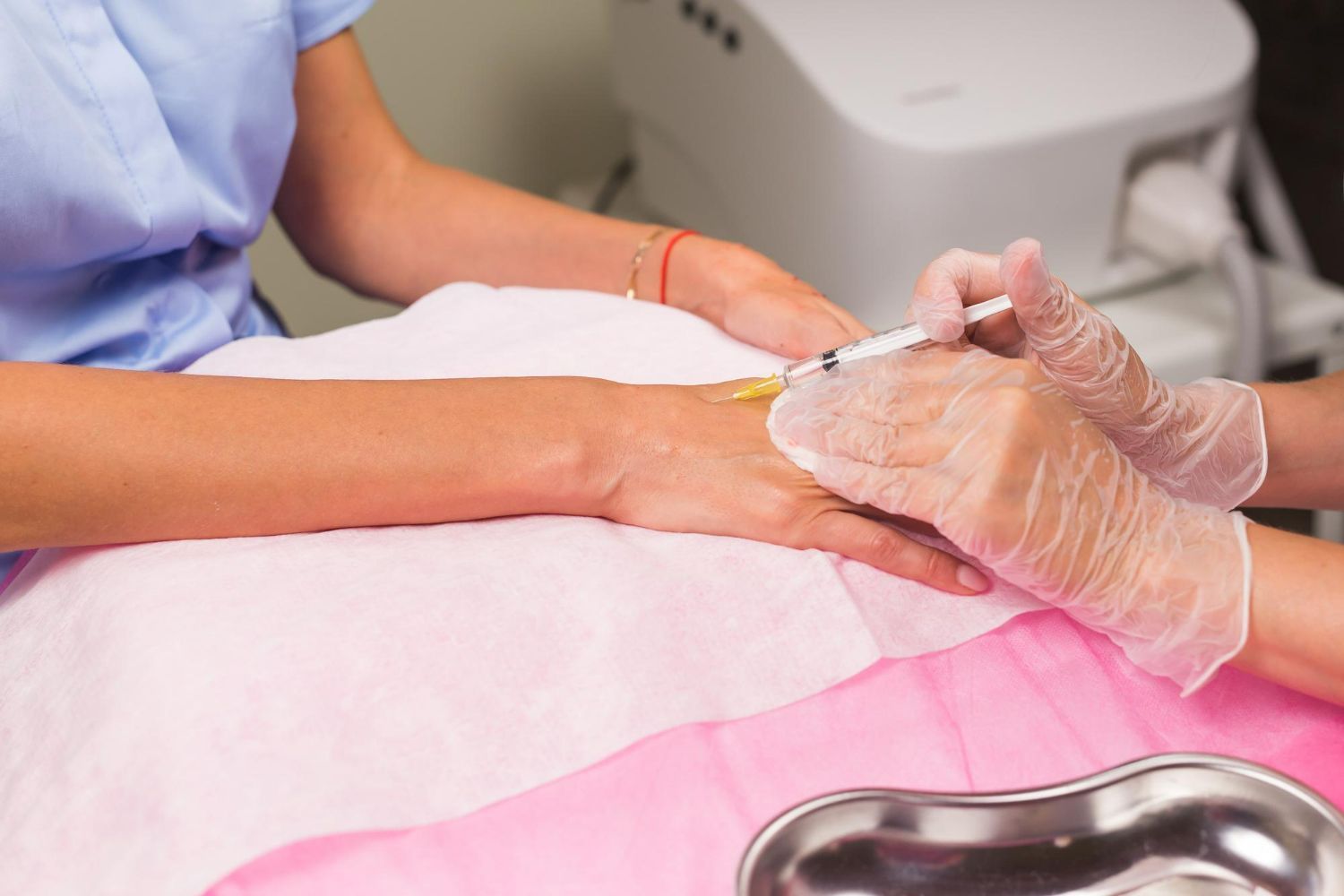 A person receiving an injection in their wrist at a medical setting.