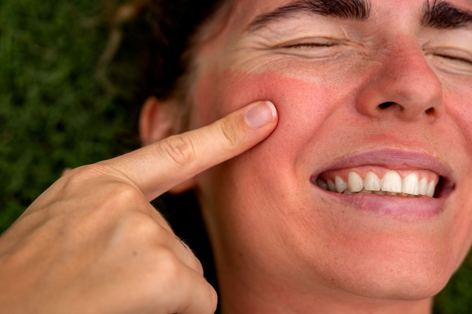 Finger pressing a red cheek as a person grimaces in pain
