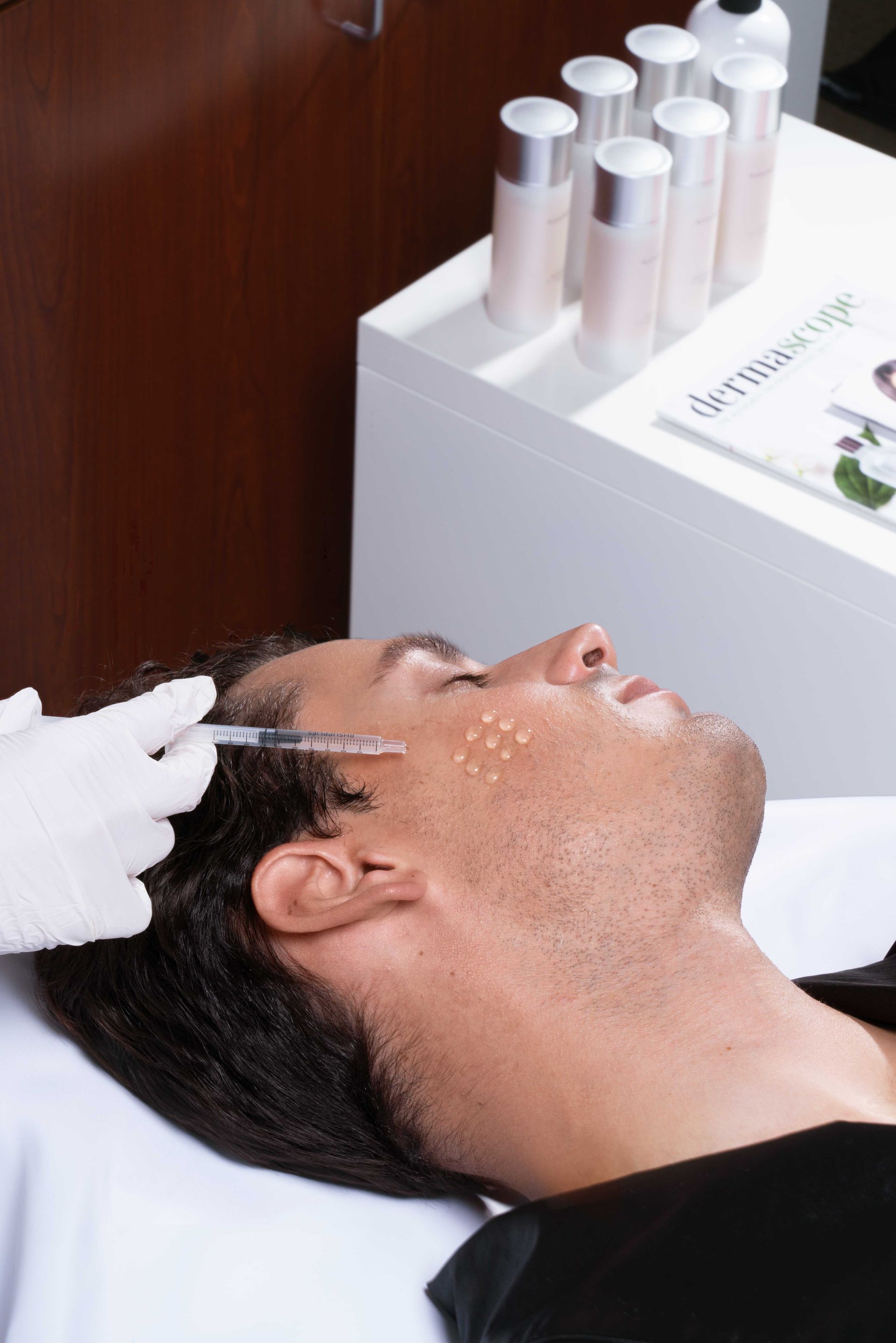 A man is getting an injection in his face at a beauty salon