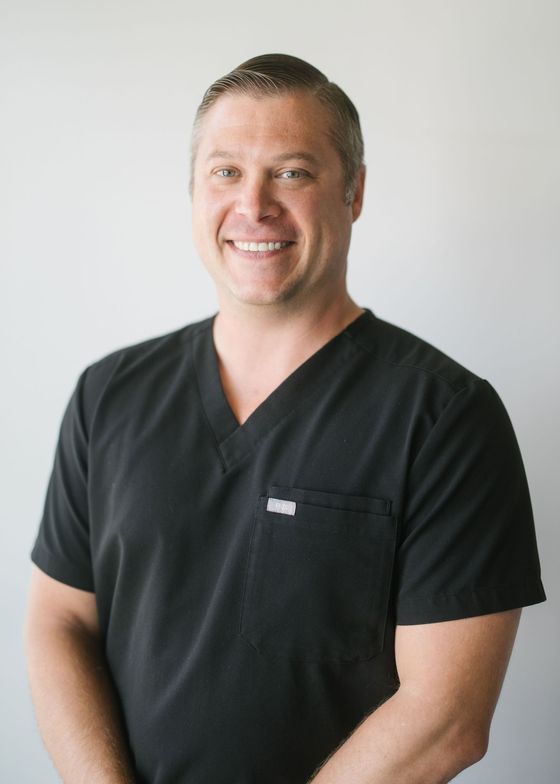 Kennedy in a black scrub top is smiling for the camera