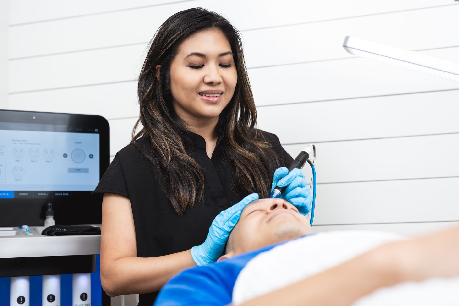 a woman is giving a person a treatment on their face .