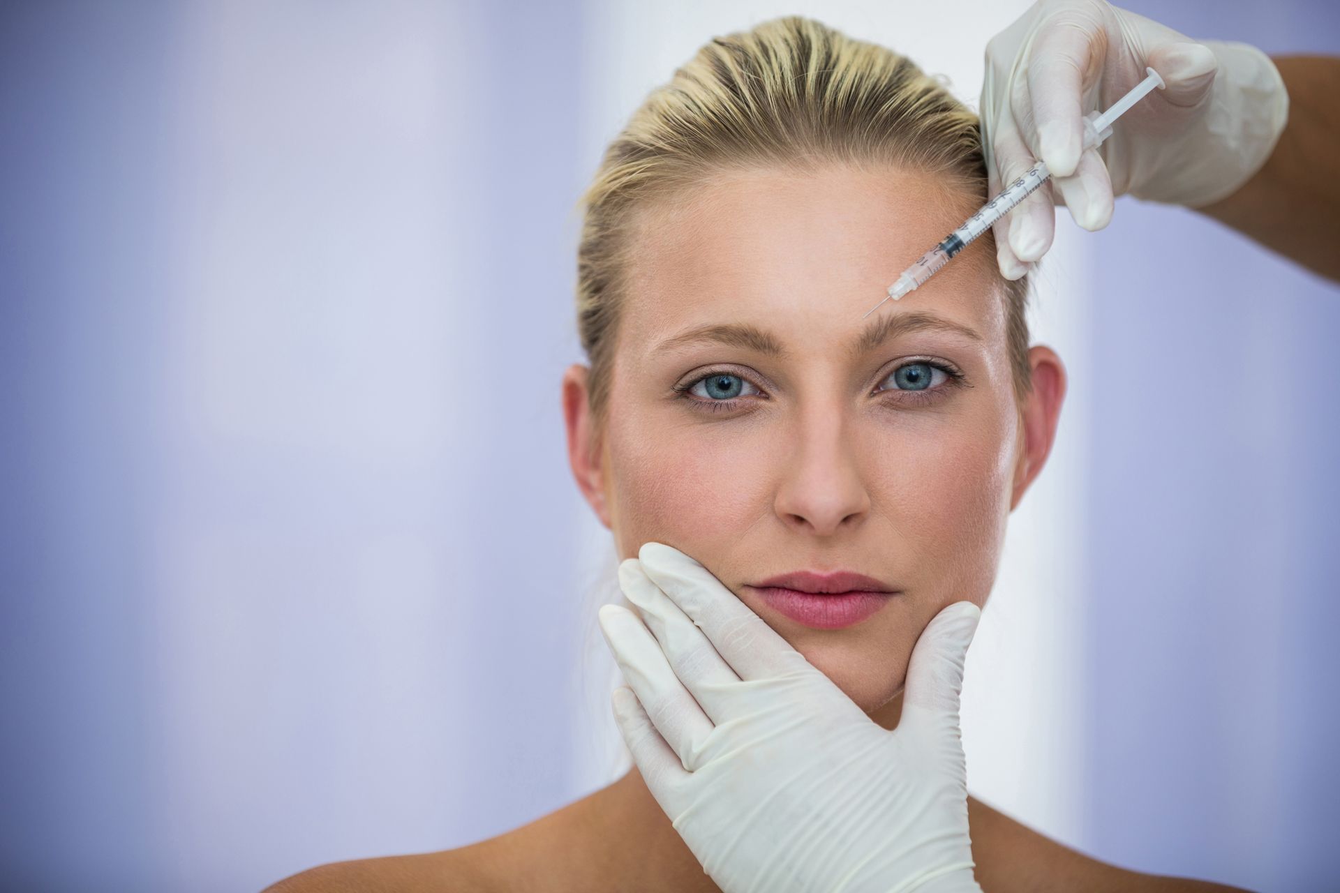 A woman is getting a botox injection in her forehead.