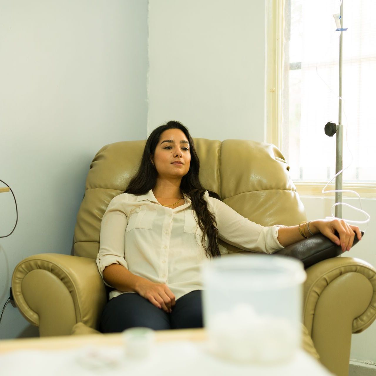 A woman is sitting in a chair with an iv in her hand.