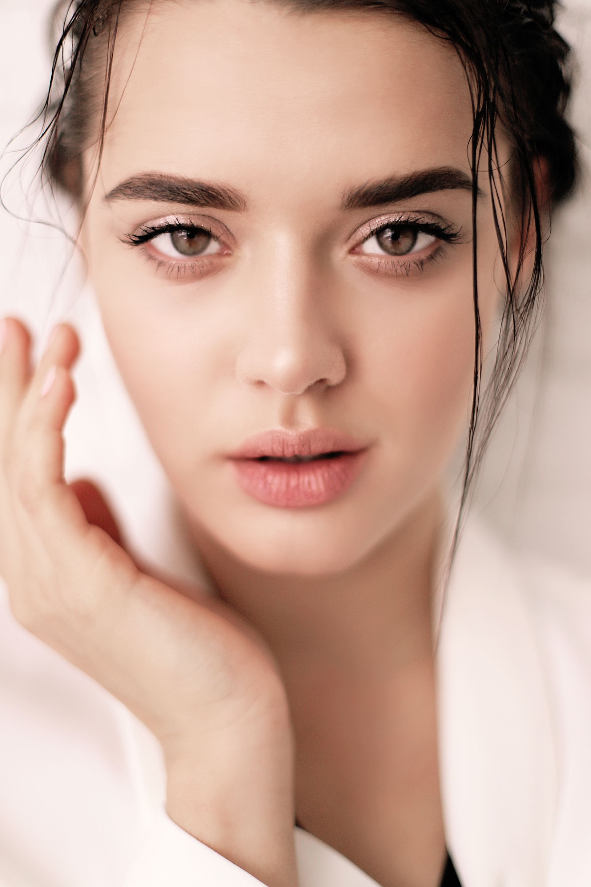 a close up of a woman 's face with her hand on her face .