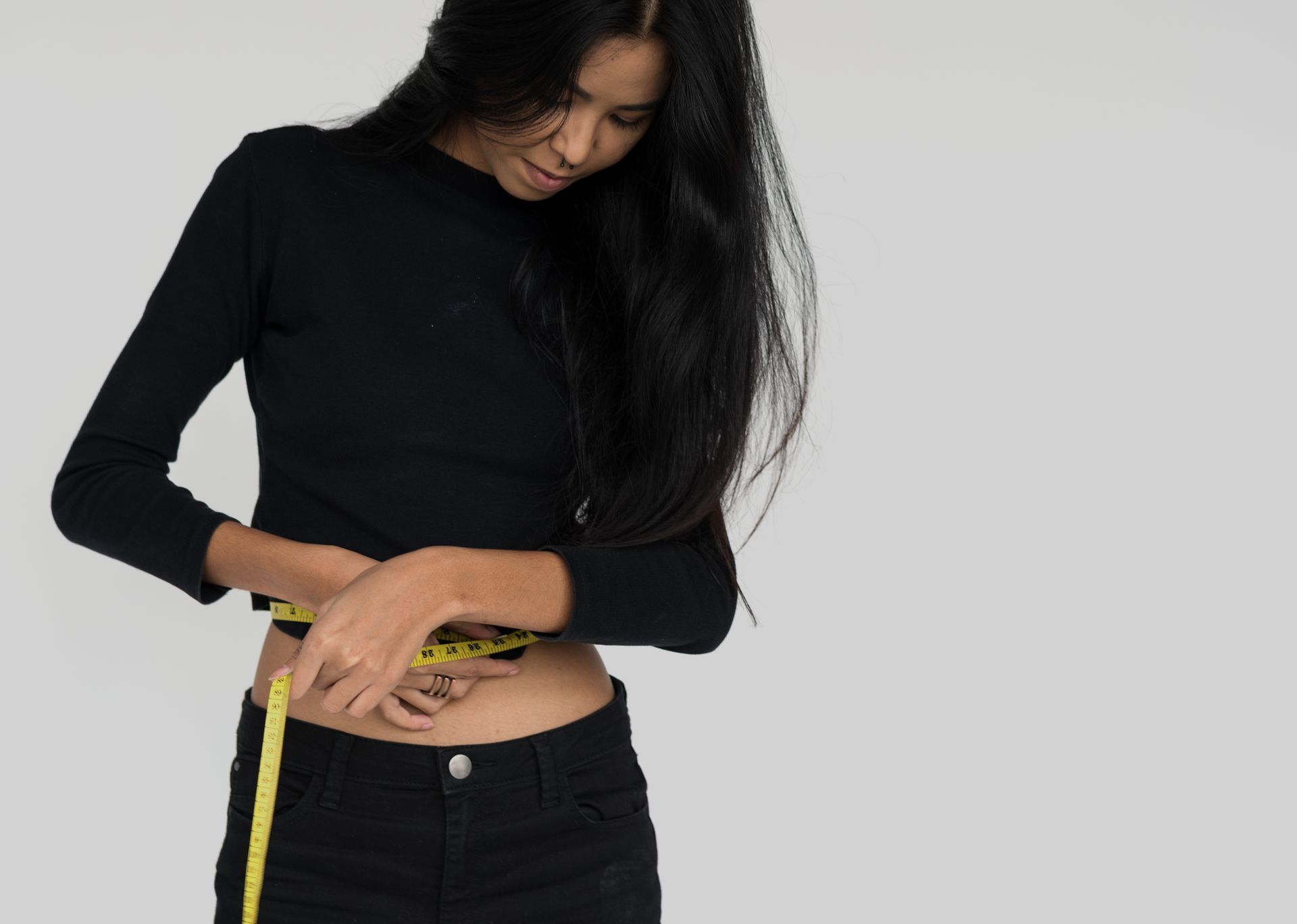 a woman is measuring her waist with a tape measure .