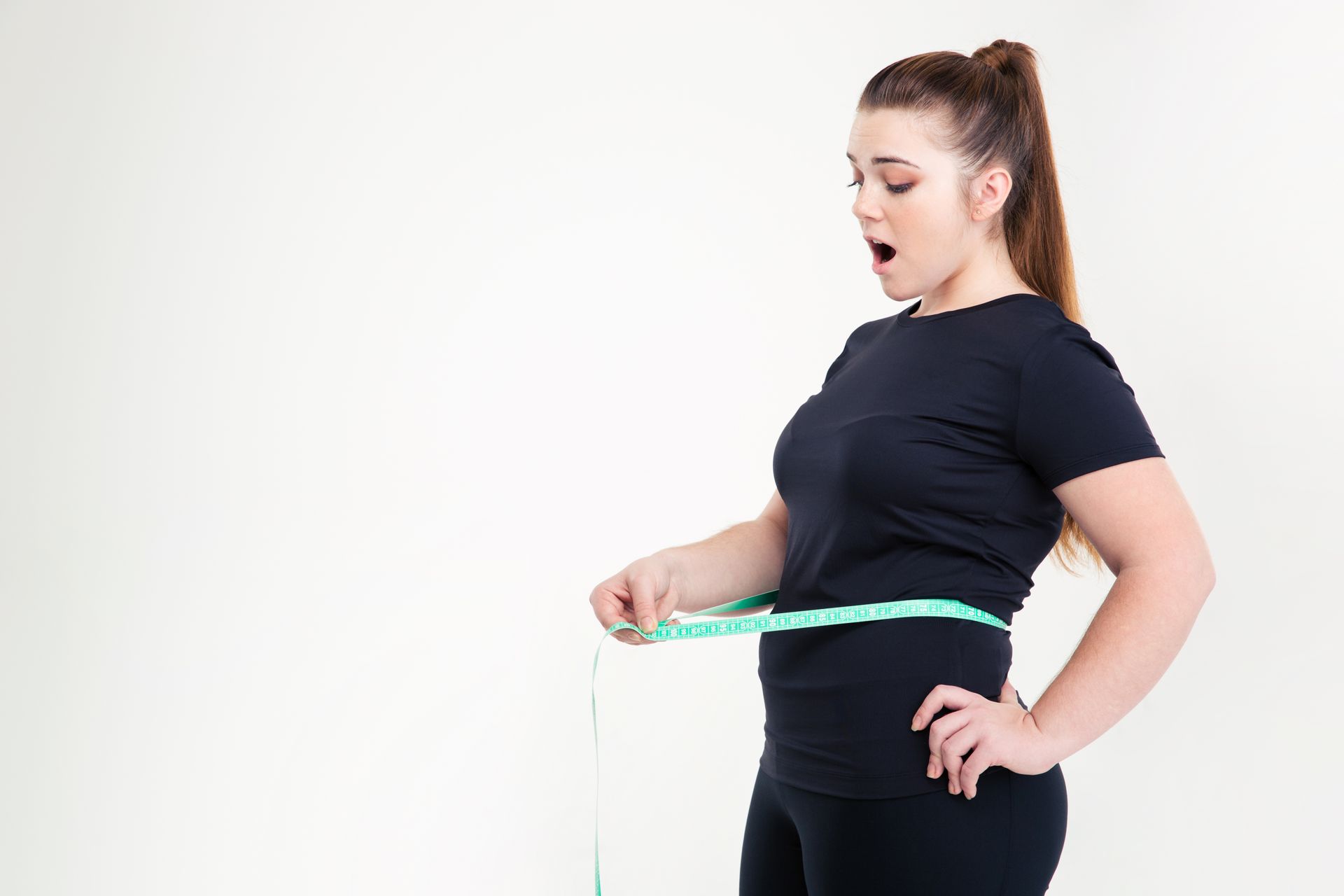 a woman is measuring her waist with a tape measure .