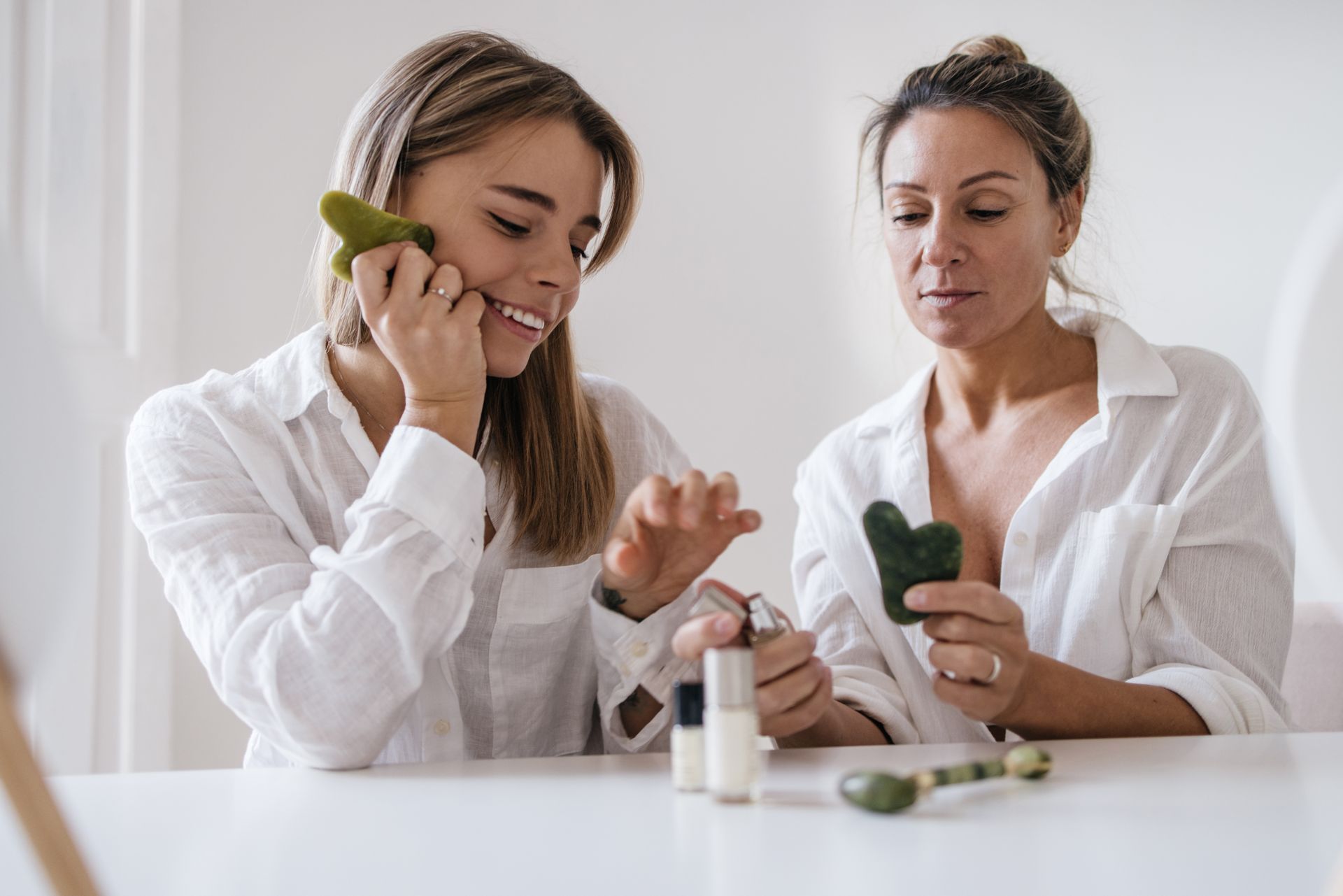 Two women are sitting at a table looking at cosmetics.