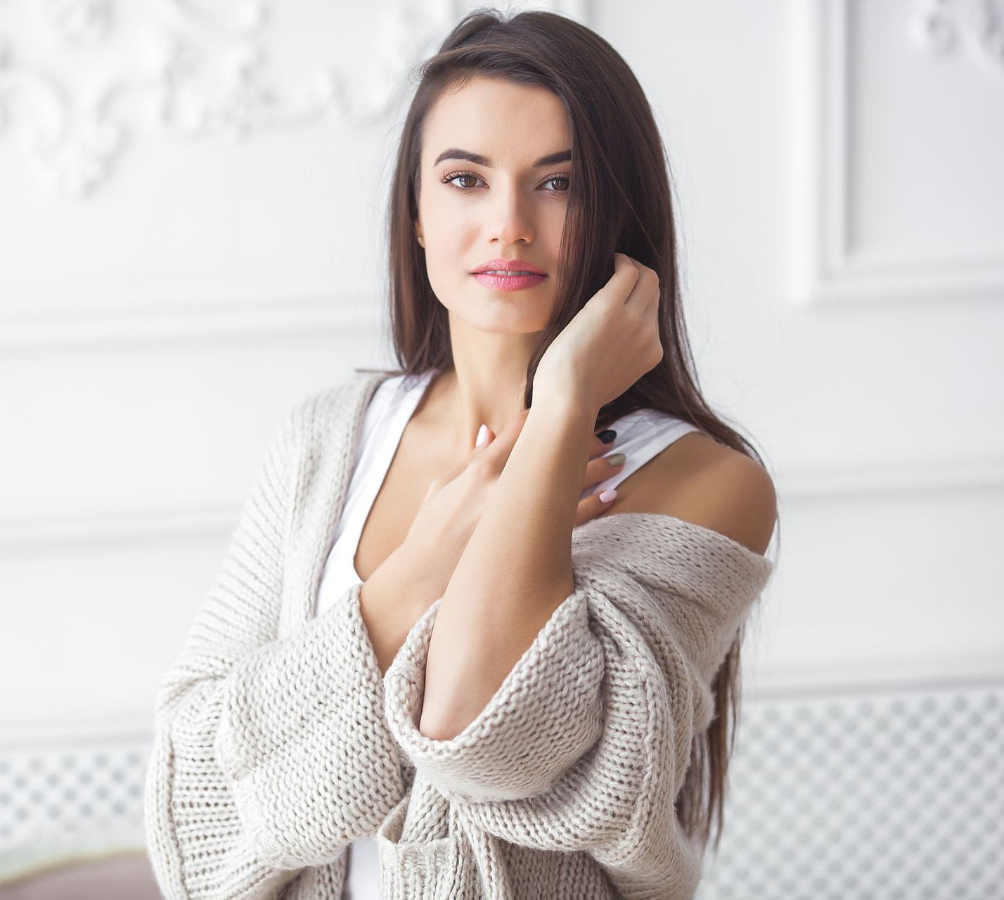 a woman is smiling and touching her face with her hands .