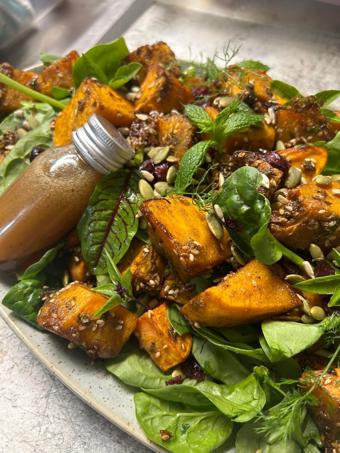 An extreme close up of a sweet potato salad with dressing in a small bottle — Amanda Douglass Catering Service in Corlette, NSW