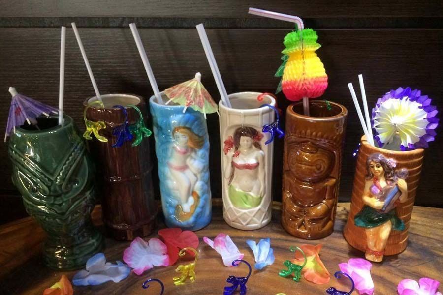 Un groupe de tasses tiki avec des pailles et des parapluies dessus