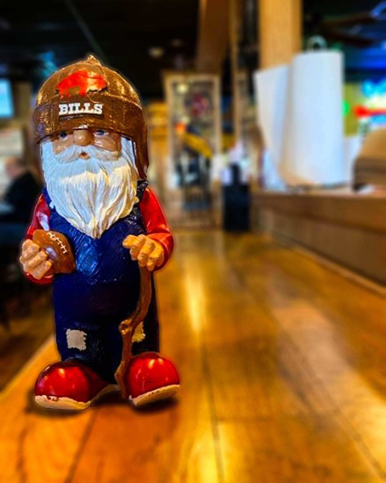 A football player statue wearing a helmet and overalls is standing on a wooden table.