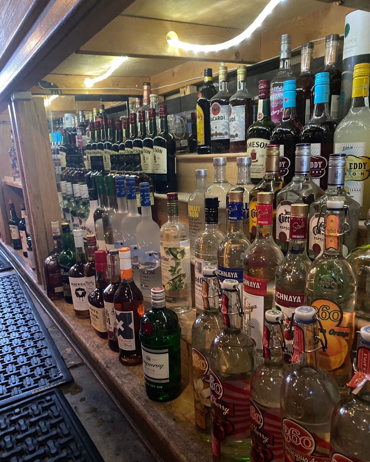Many bottles of liquor are lined up on a bar