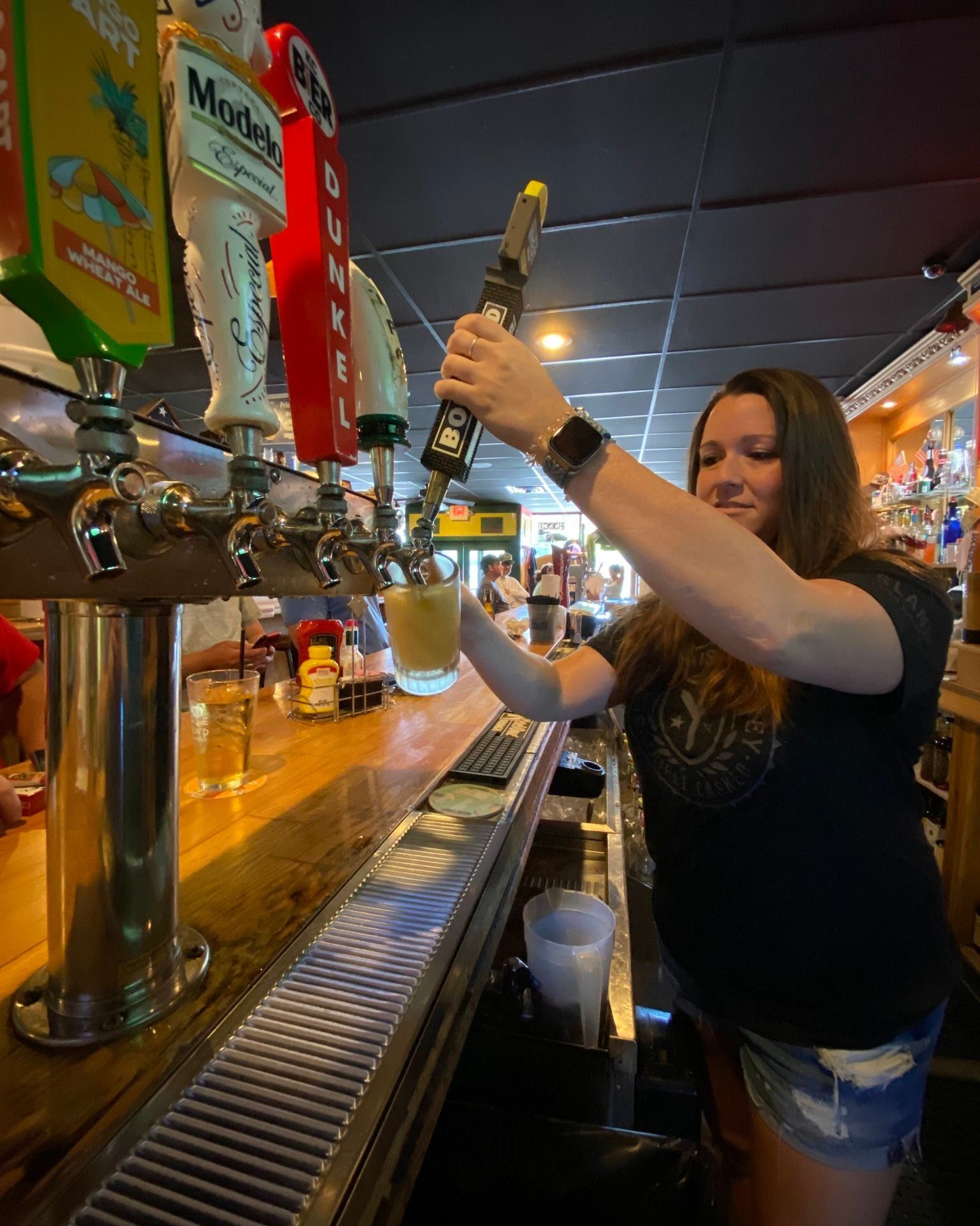 A woman is pouring beer from a tap at a bar.