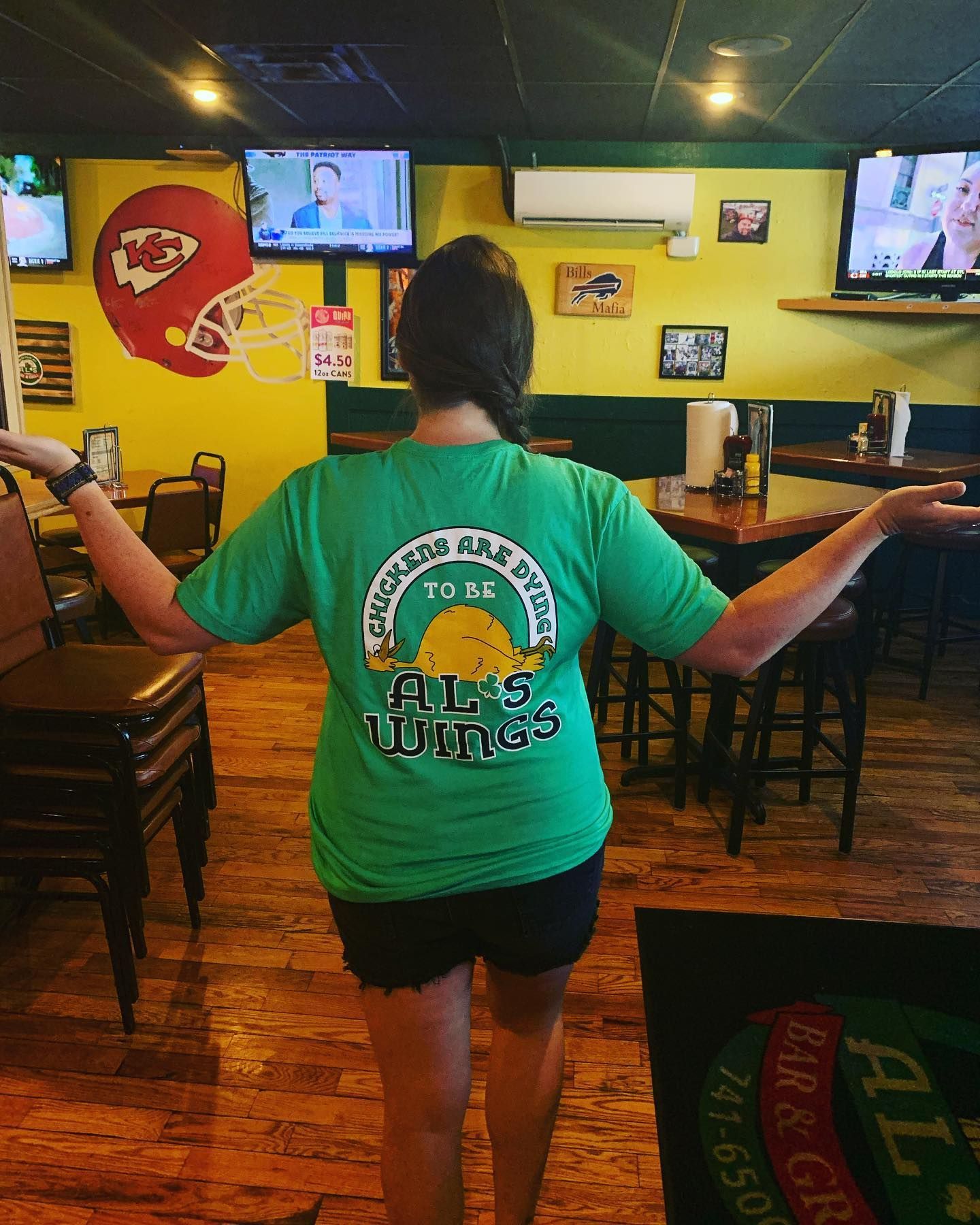 A woman wearing a green shirt that says al's wings