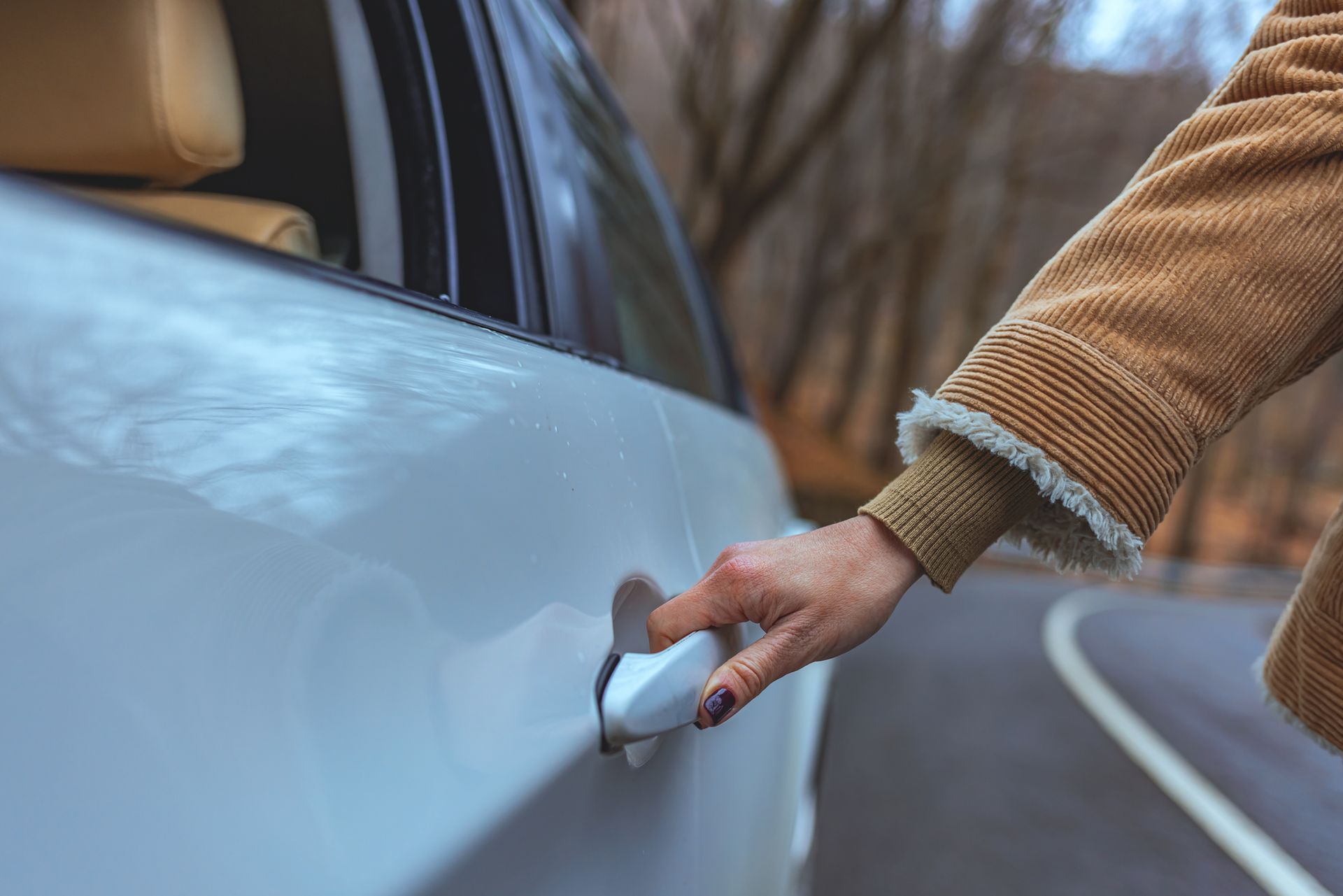 A person is opening the door of a car on a road.
