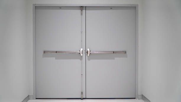 A pair of white doors with a metal handle in a hallway.