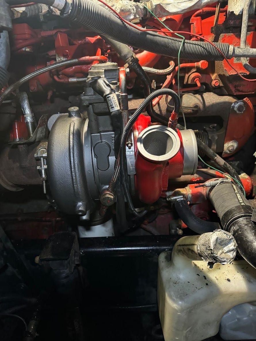 Close-up of a car engine bay with hoses, metal parts, and a coolant reservoir.