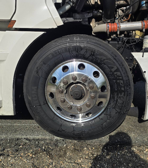 Close-up of a truck wheel with a chrome hubcap and black tire on a pavement surface.