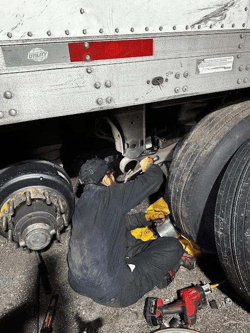 Overturned semi-truck on roadside, with another truck nearby and debris on the ground