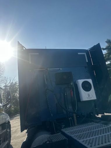 Dark utility truck with open rear door and mounted equipment in bright sunlight