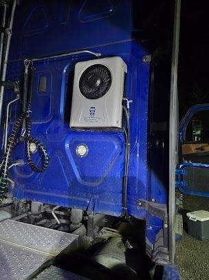 Blue truck cab interior with a wall-mounted white air conditioner unit and seat visible