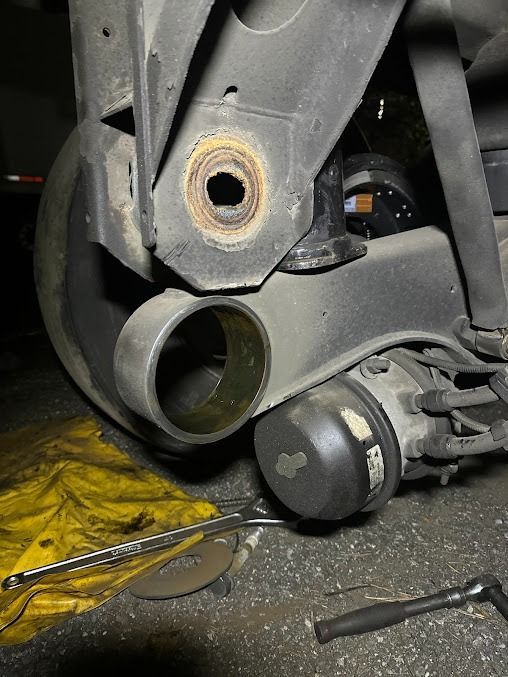 Close-up of a damaged vehicle suspension and wheel hub with tools on the ground.