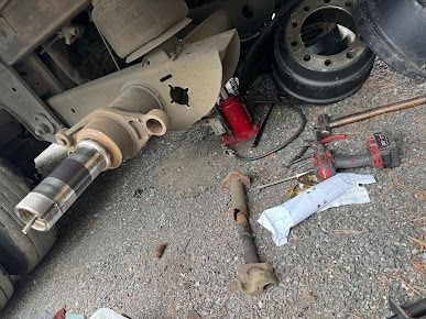 Damaged truck wheel area with detached tire, tools, and debris on the ground