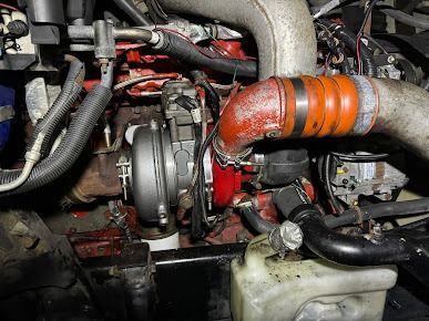 Close-up of a turbocharged engine with red and orange hoses and metallic components.