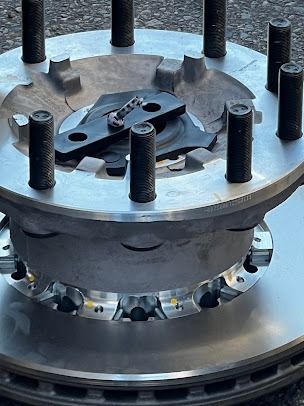 Close-up of a metal industrial component with bolts and a circular base on a machine surface