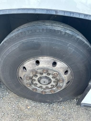 Close-up of a truck wheel and tire with a metal rim on gravel.