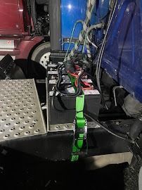 Truck cab interior with blue and red panels, wiring, a battery, and a metal step platform