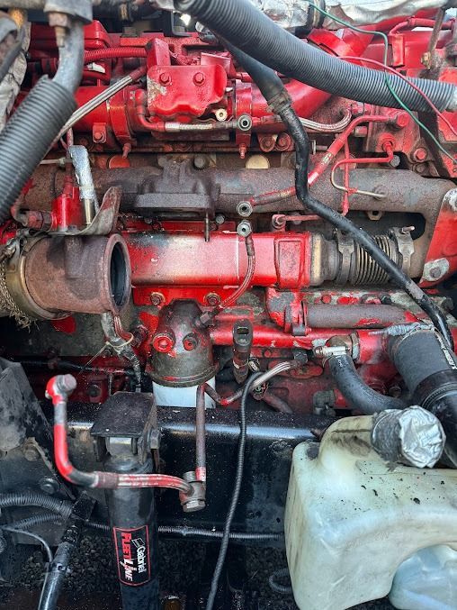 Red engine bay with hoses, pipes, and a translucent coolant reservoir in the lower right.