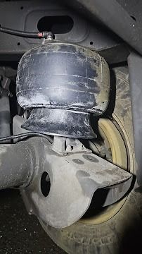 Close-up of a car suspension air spring and wheel well with dusty metal components