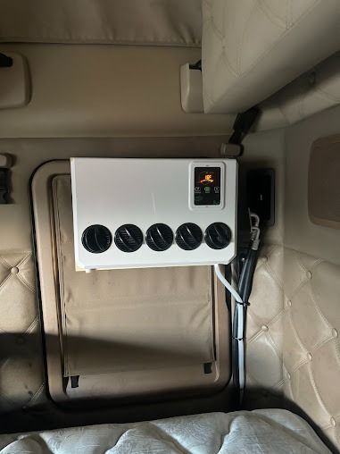 White control panel with five black knobs mounted inside a beige vehicle interior