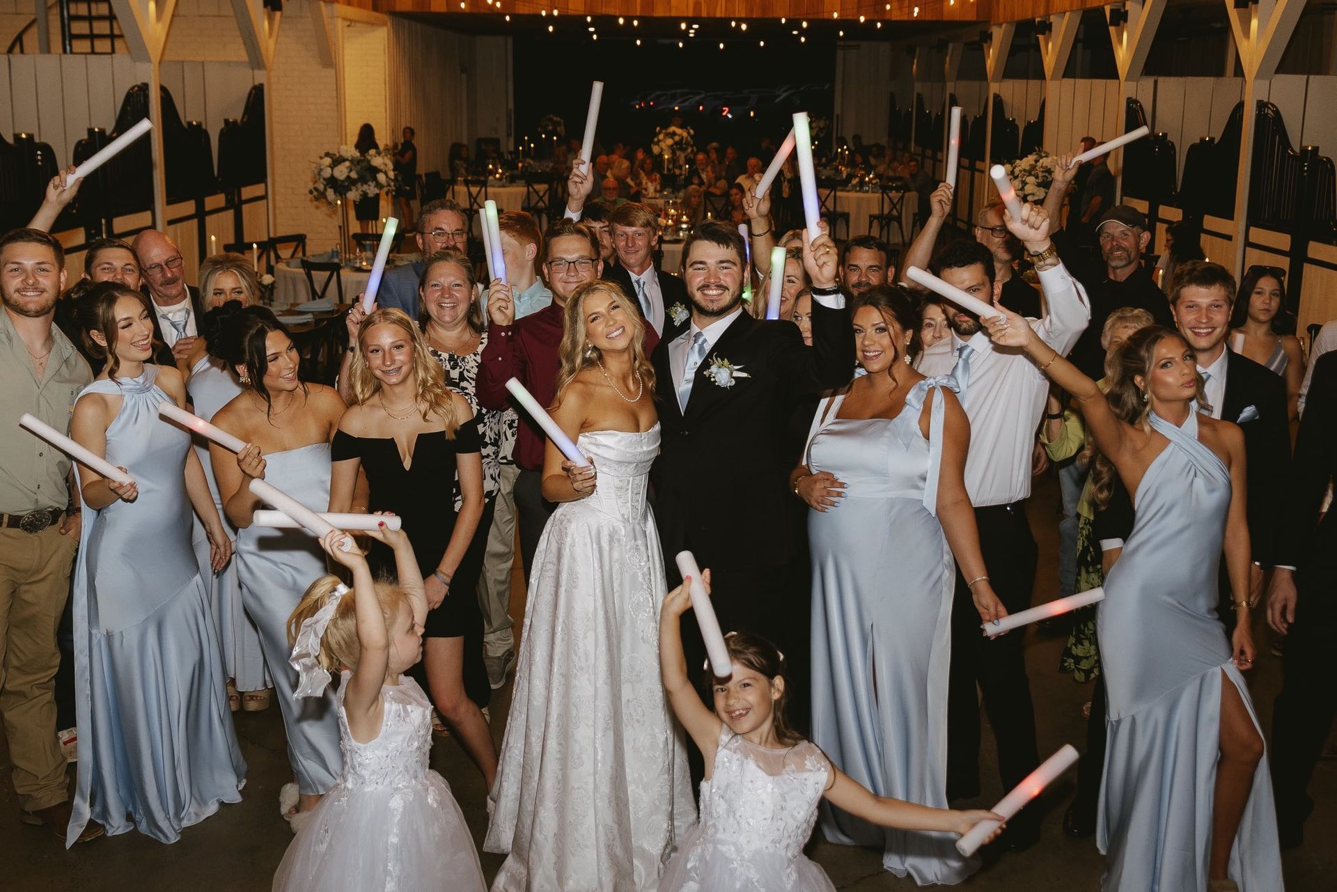 bride and groom with wedding party holding glow sticks