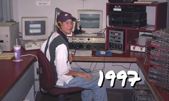 Person at a computer desk with multiple monitors in a cluttered room, labeled “1997”