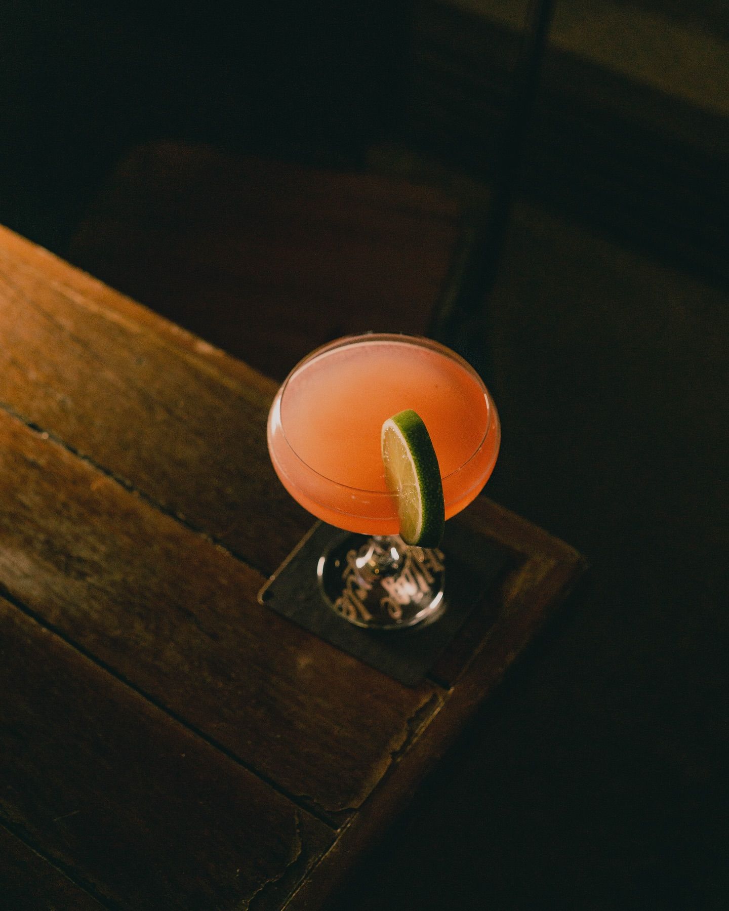 Cocktail in a Coupe Glass With a Lime Garnish, on a Wooden Table — Village Bicycle Noosa in Noosa Heads, QLD