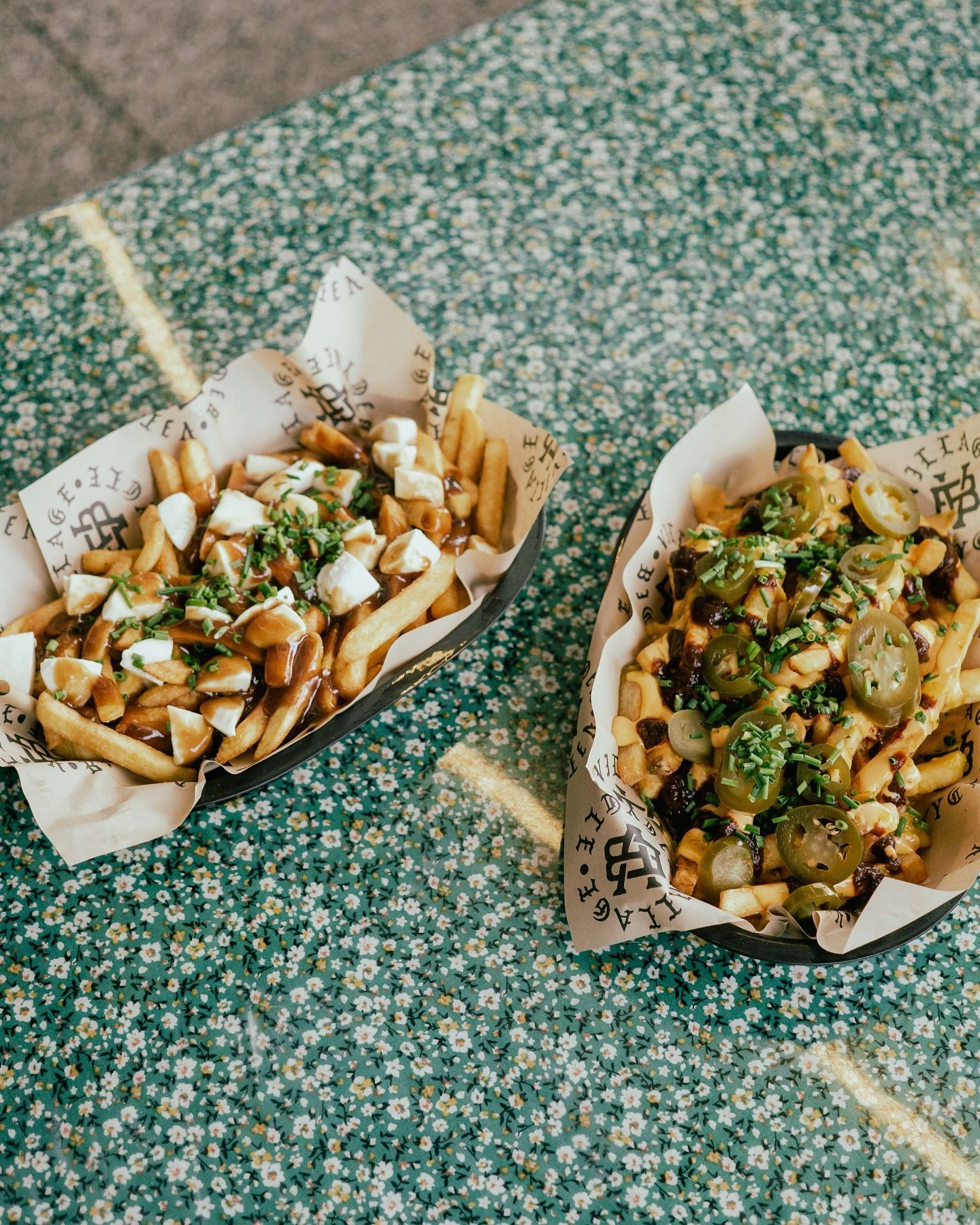 Two Baskets of Fries on Floral Table, One With Cheese Curds and Gravy — Village Bicycle Noosa in Noosa Heads, QLD