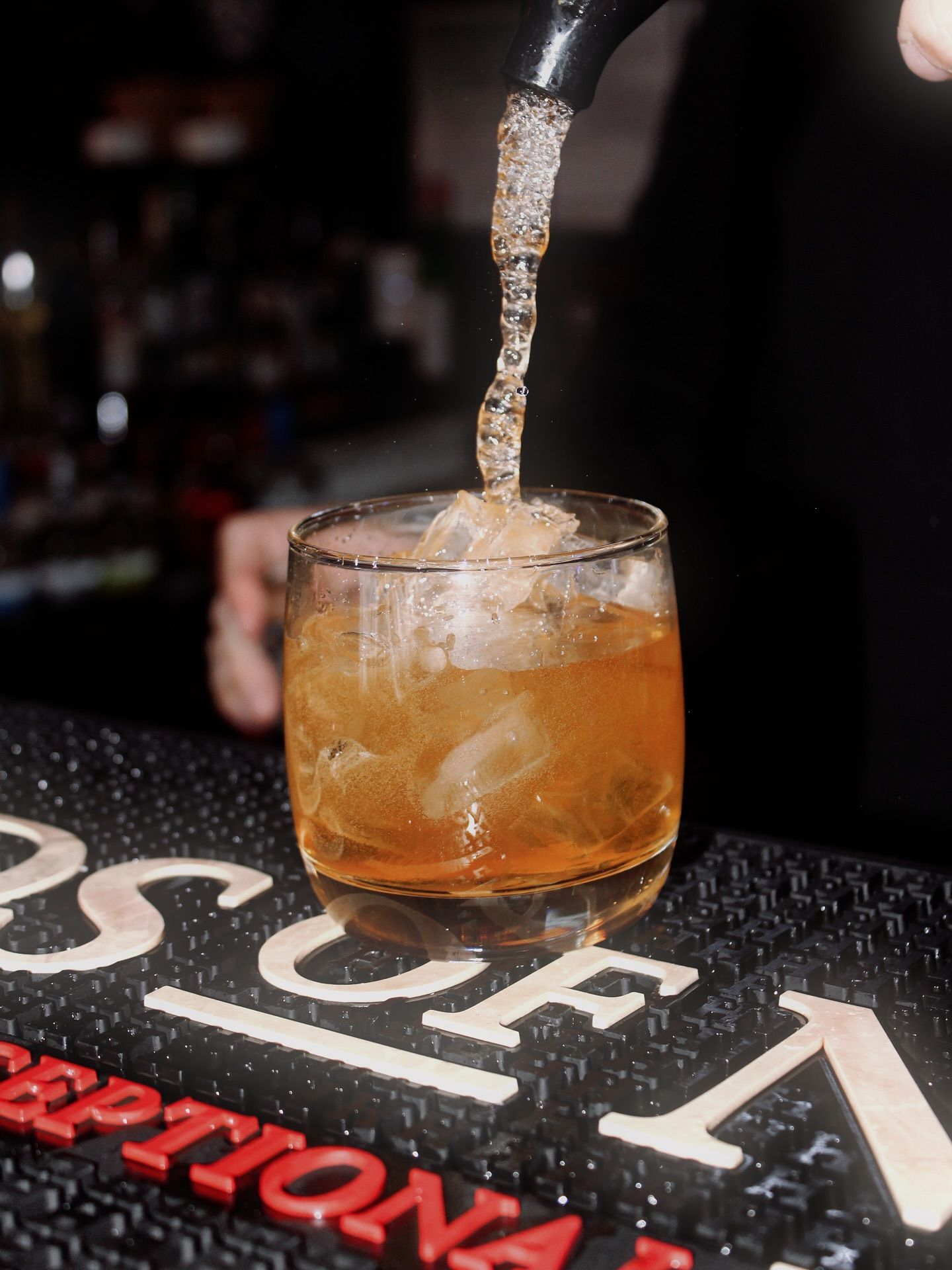 A Cocktail Being Poured From a Black Spout Into a Rocks Glass With Ice on a Bar — Village Bicycle Noosa in Noosa Heads, QLD
