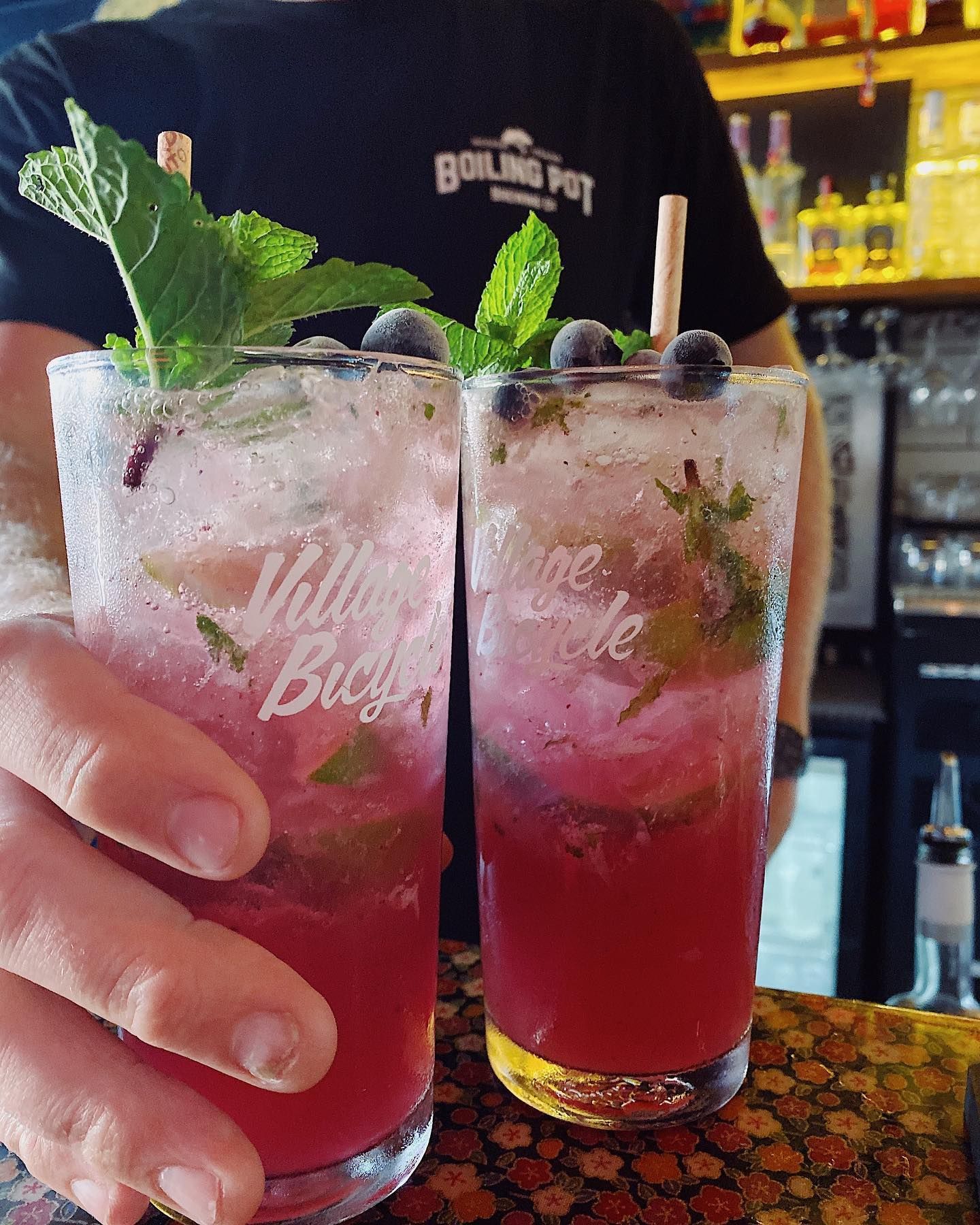 Two Blueberry Mojitos With Mint Garnish, Held by a Person in a Bar — Village Bicycle Noosa in Noosa Heads, QLD