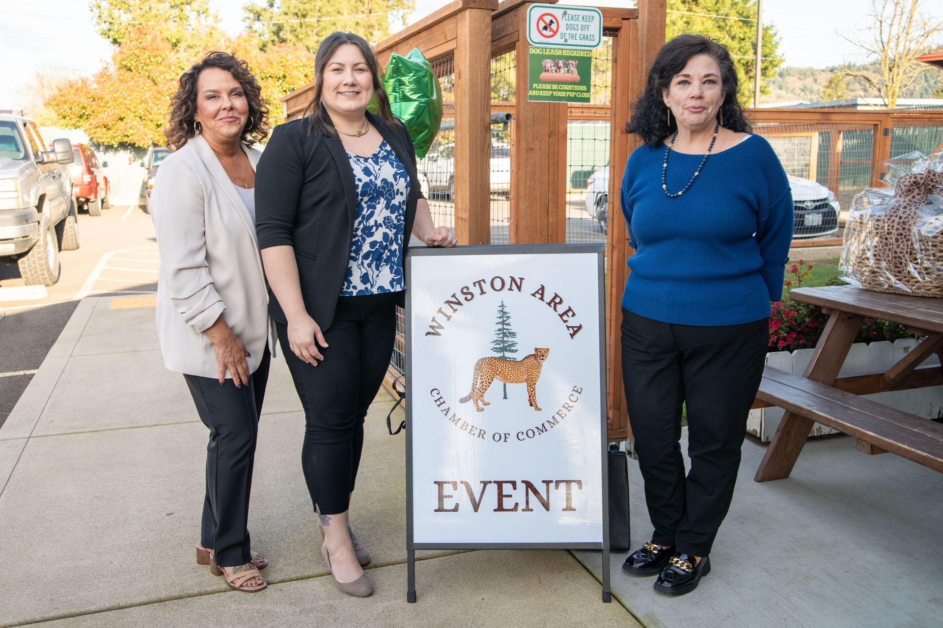 Three women standing near a sign that reads
