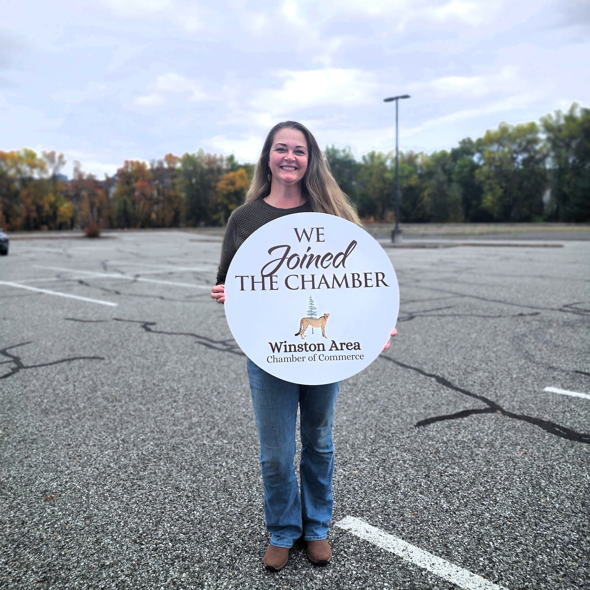 A woman with long blonde hair is smiling and wearing a striped shirt.