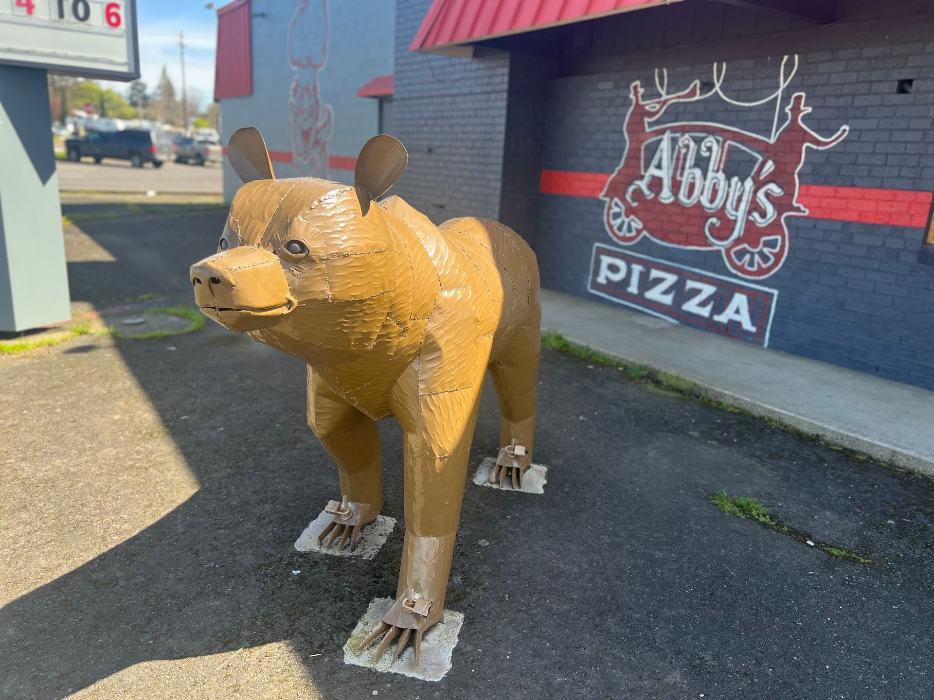 A statue of a bear in front of abby 's pizza