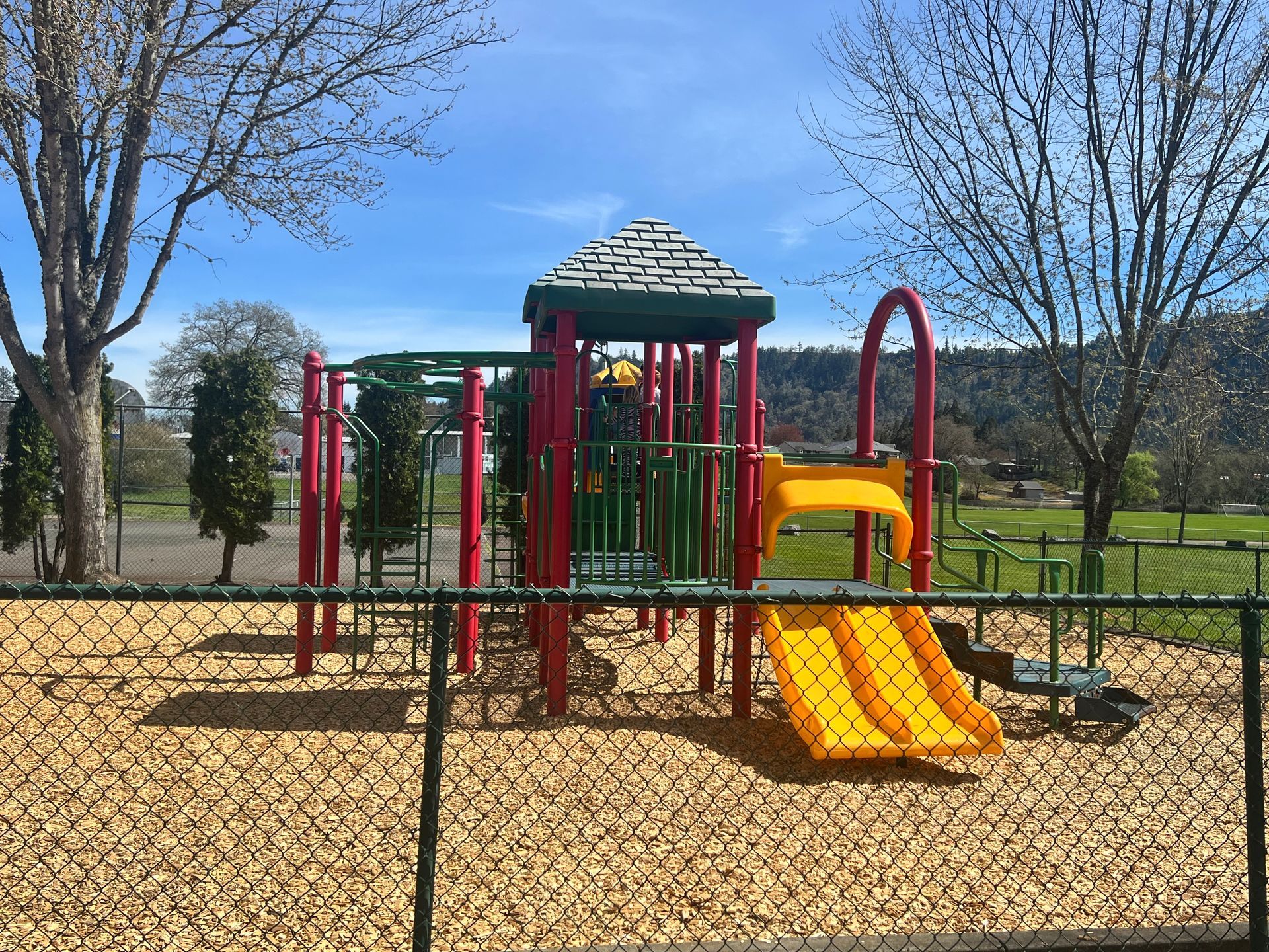 A playground with a yellow slide and a red tower