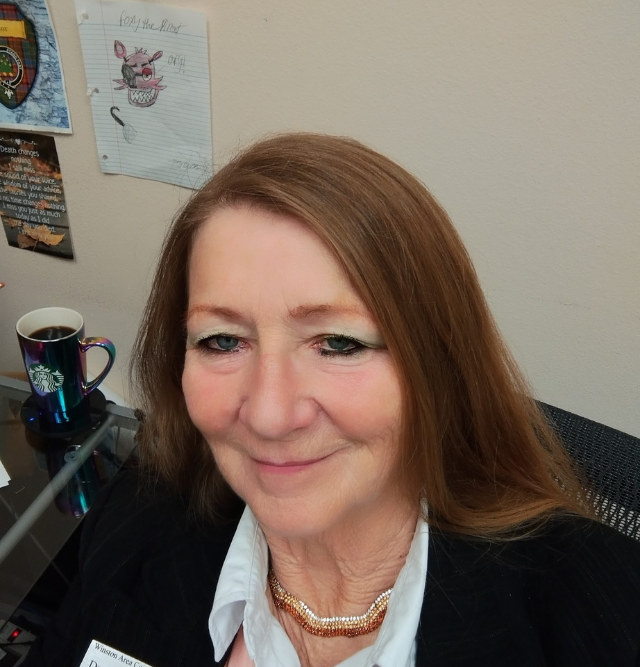 A woman sitting at a desk with a cup of coffee