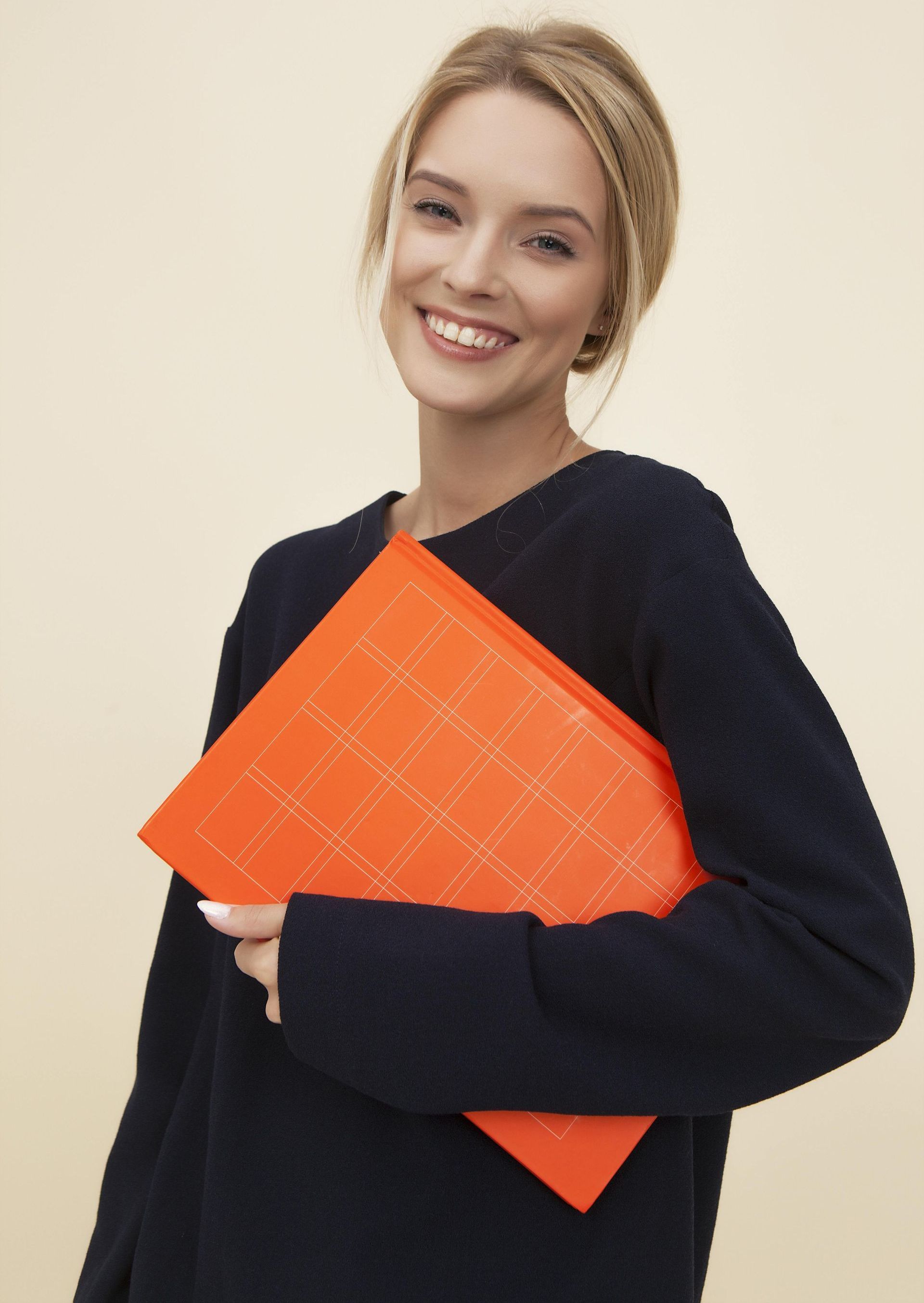A woman in a black sweater is holding an orange folder
