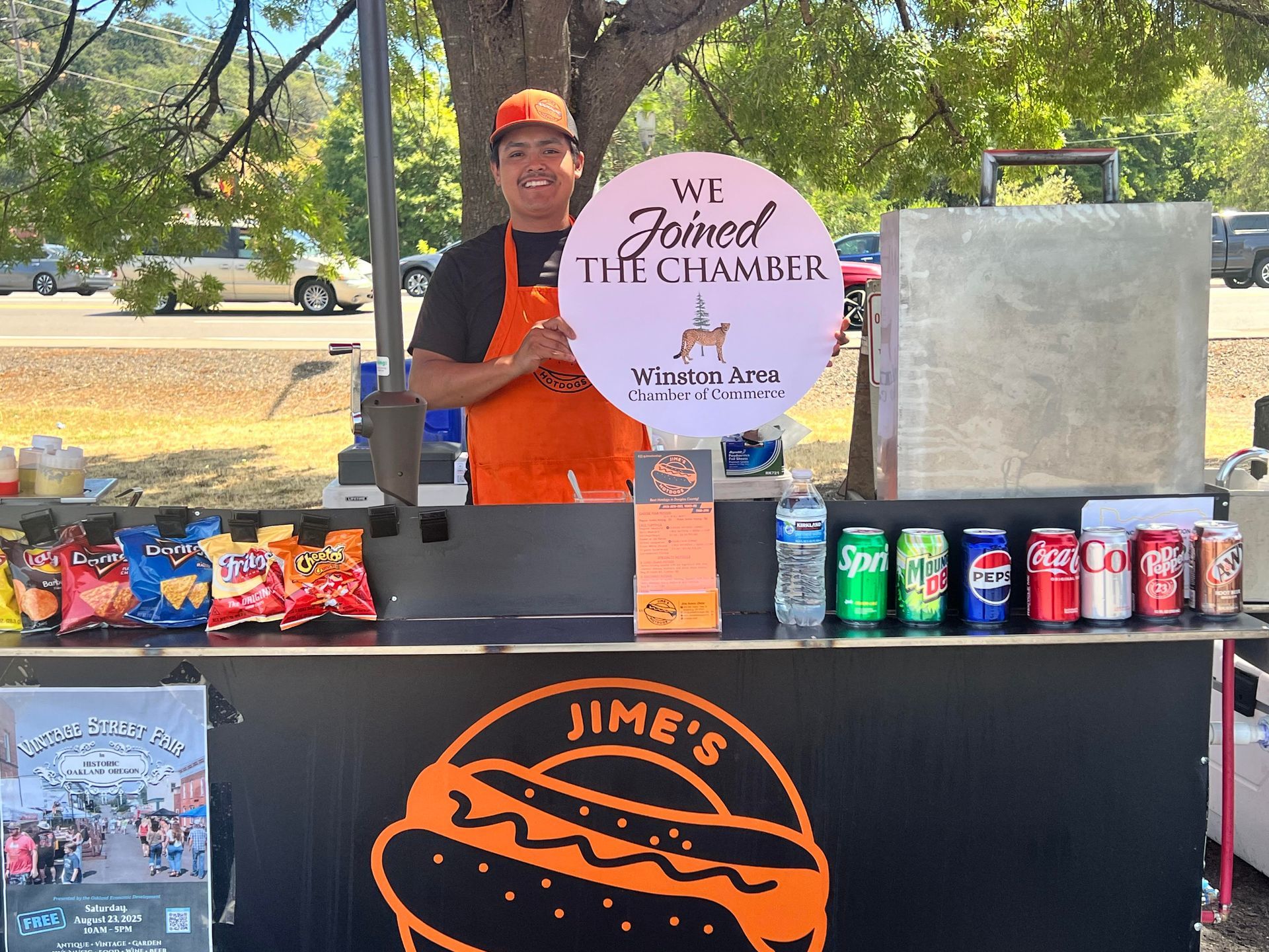 A person stands behind a food cart displaying