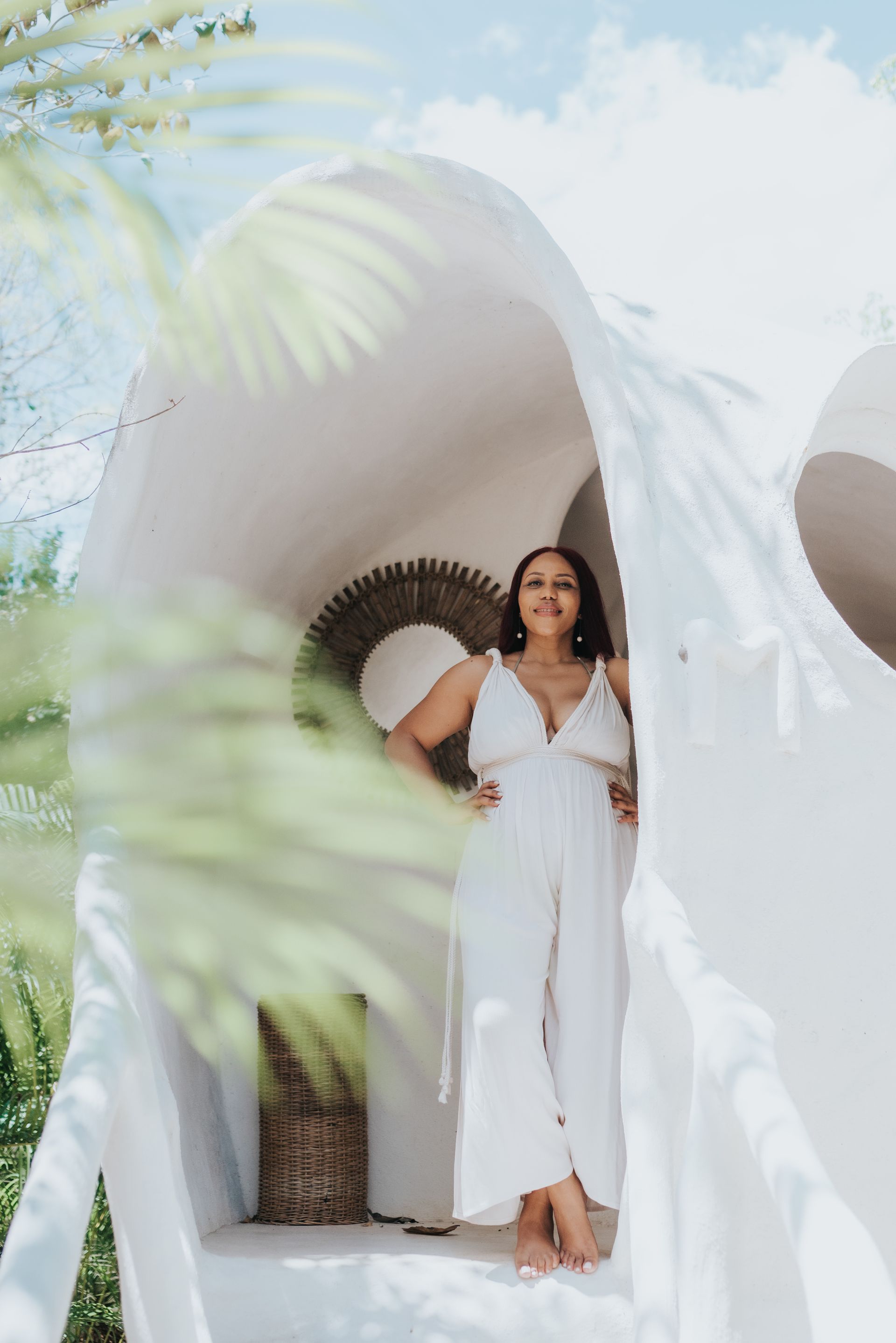 A woman in a white dress is standing in front of a white building.