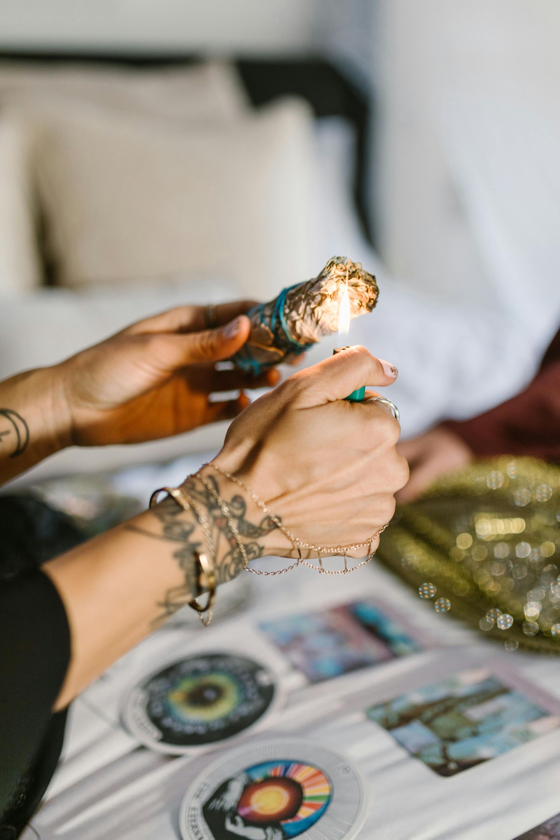 A person is holding a candle in their hand while sitting at a table with tarot cards.