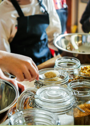 A person is scooping something out of a jar with a spoon